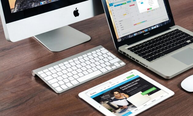 A sleek office desk setup featuring Apple devices: iMac, MacBook, and iPad.