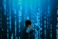 Silhouette of a person using a smartphone surrounded by digital binary code projections.